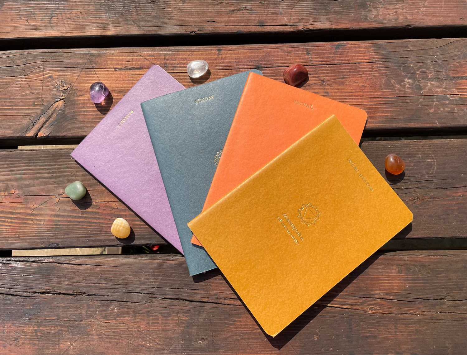 Quadernini colorati e pietre dei Chakra utilizzati nella pratica del journaling nello Yoga Facciale